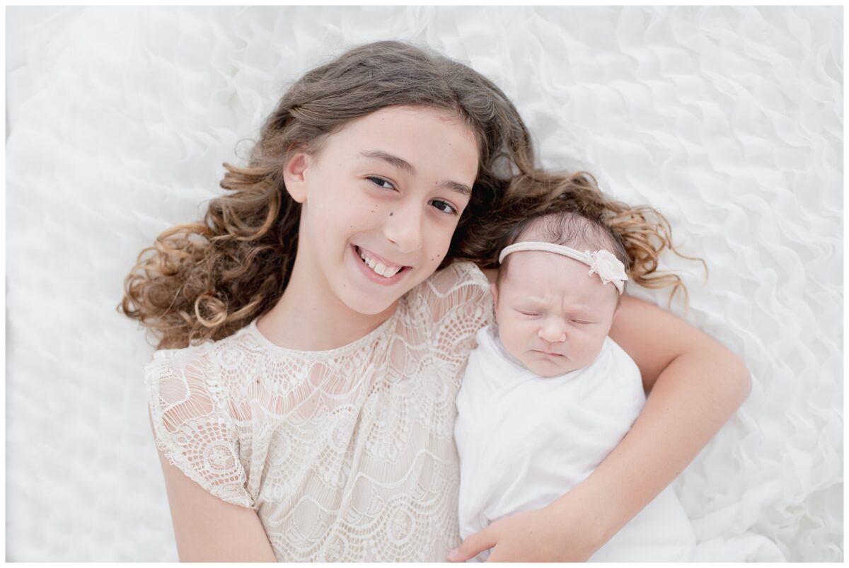 Big sister holding her newborn baby sister for newborn session