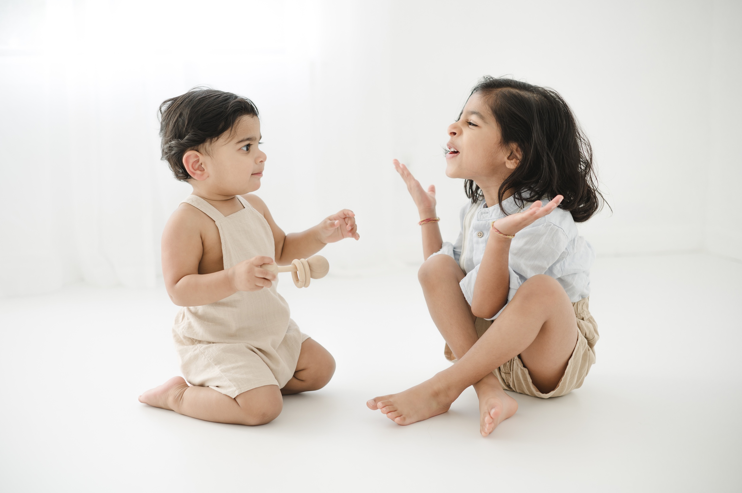 A young boy sits on the floor with his baby brother playing with wooden toys and laughing before visiting an austin pediatrician