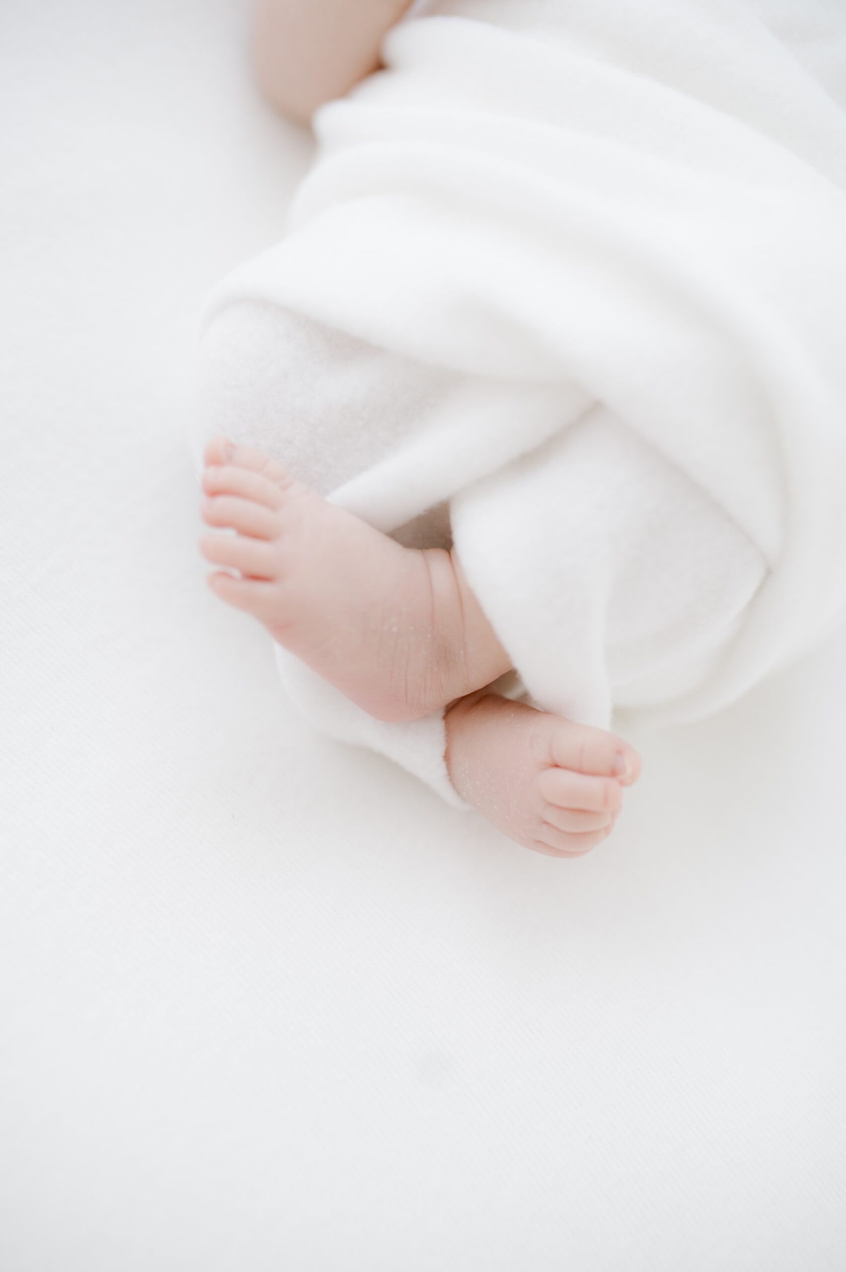 Details of a newborn baby's feet in a white swaddle after some infant swim lessons in austin